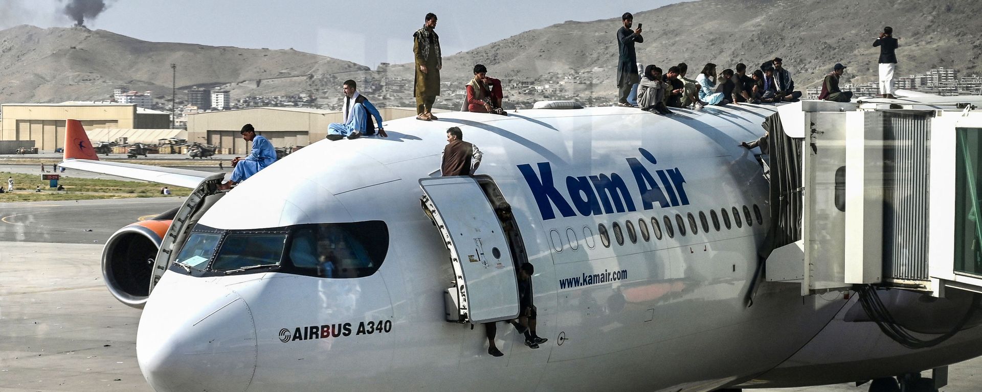 Afghan people climb atop a plane as they wait at the airport in Kabul on August 16, 2021, after a stunningly swift end to Afghanistan's 20-year war, as thousands of people mobbed the city's airport trying to flee the group's feared hardline brand of Islamist rule Afghan people climb atop a plane as they wait at the airport in Kabul on August 16, 2021, after a stunningly swift end to Afghanistan's 20-year war, as thousands of people mobbed the city's airport trying to flee the group's feared hardline brand of Islamist rule - Sputnik International, 1920, 15.08.2022