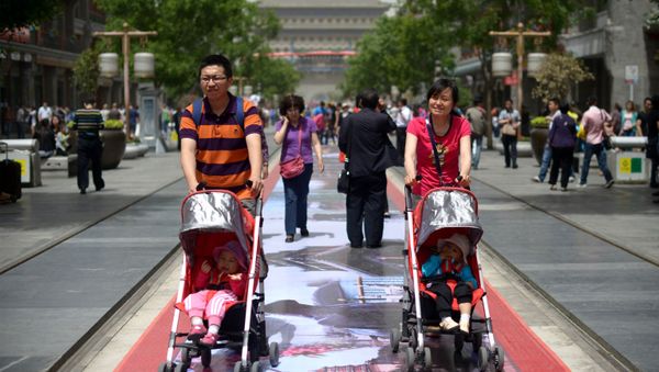 A couple pushes their young children in prams along a street in Beijing on May 19, 2013 - Sputnik International