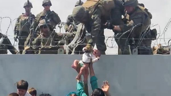 A baby is handed over to the American army over the perimeter wall of the airport for it to be evacuated, in Kabul, Afghanistan, August 19, 2021, in this still image taken from video obtained from social media. - Sputnik International
