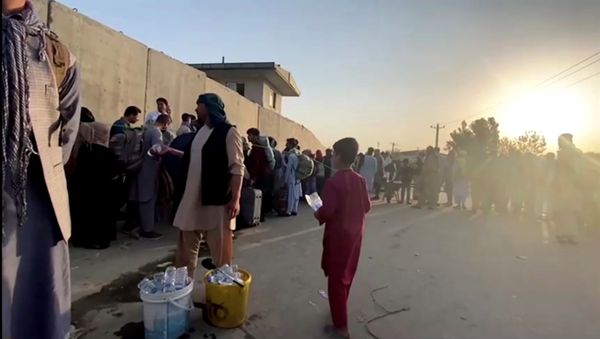 A man instructs people to queue as they stand with their belongings outside Kabul airport, Afghanistan, August 22, 2021 in this still image taken from video - Sputnik International
