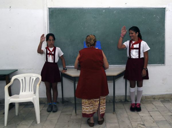 Students salute as a woman casts her ballot during Cuba's first local elections since a historic thaw in relations with the United States, in Havana, Cuba.  - Sputnik International