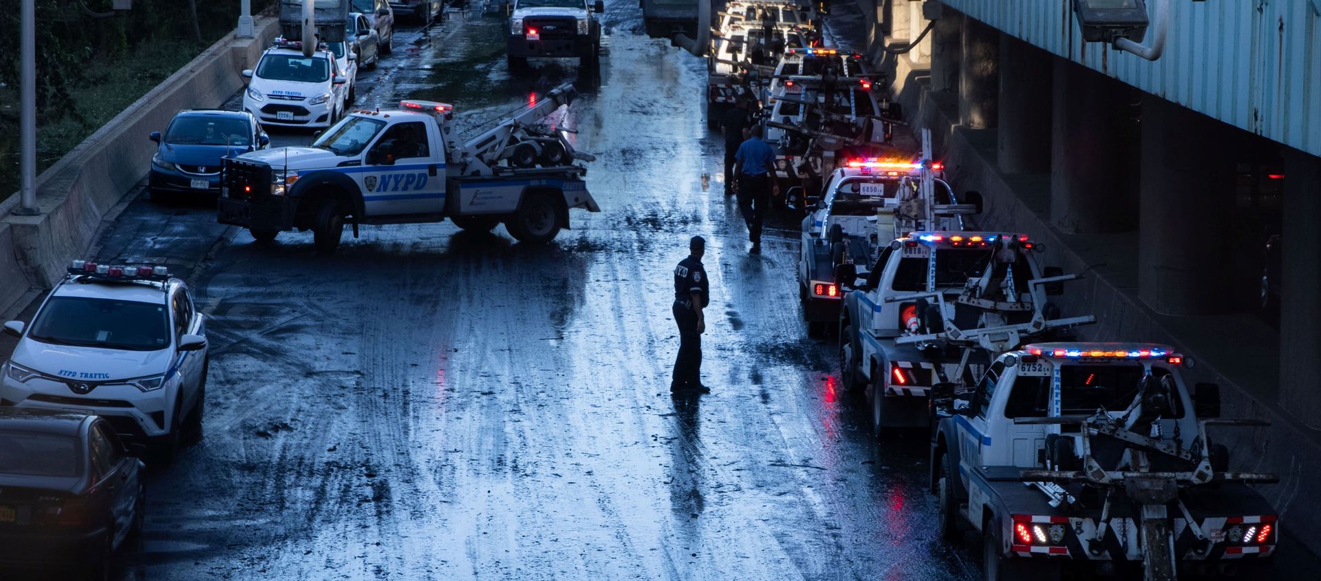 A member of the NYPD supervises tow trucks clearing cars abandoned on the Major Deegan Expressway after the remnants of Tropical Storm Ida brought drenching rain, flash floods and tornadoes to parts of the northern mid-Atlantic, in the Bronx borough of New York City, U.S - Sputnik International, 1920, 03.09.2021