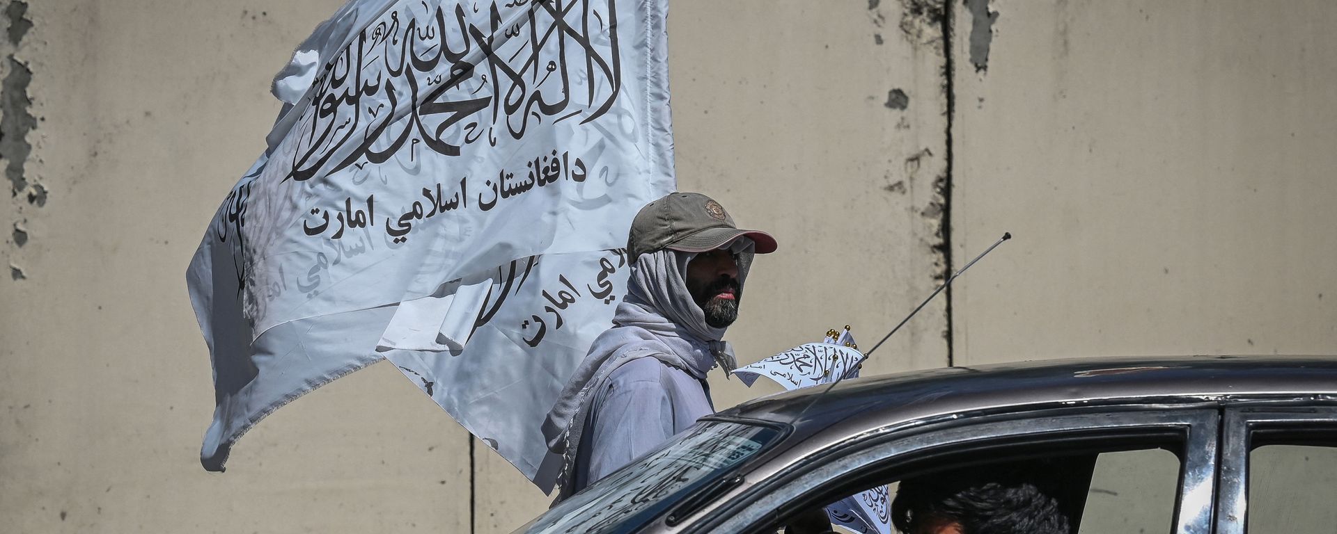 A mobile hawker carries Taliban flags as commuters make their way along a road in Kabul on September 5, 2021.  - Sputnik International, 1920, 06.11.2021