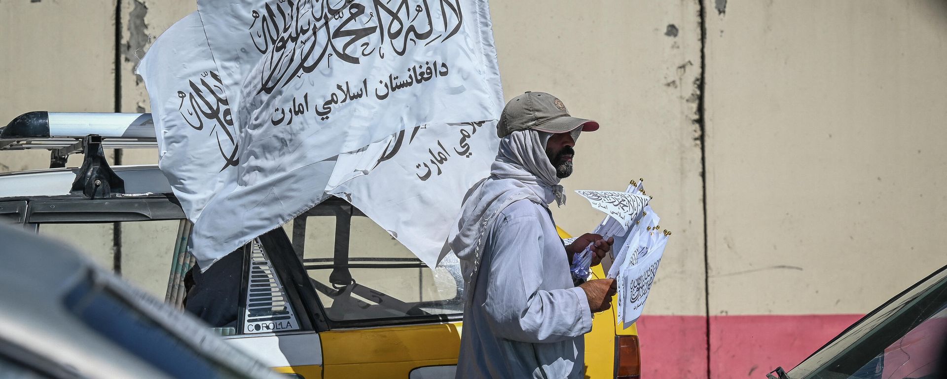 A mobile hawker carries Taliban flags as commuters make their way along a road in Kabul on September 5, 2021. A mobile hawker carries Taliban flags as commuters make their way along a road in Kabul on September 5, 2021. - Sputnik International, 1920, 07.09.2021