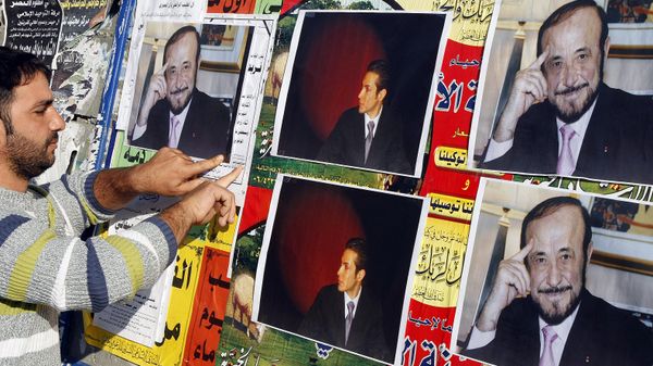 CORRECTING NAME OF RIFAATS SON: A member of the Alawite community pastes on a wall, in the northern Lebanese city of Tripoli 06 December 2007, pictures of Syrian opposition leader Rifaat al-Assad (R) and his son Ribal - Sputnik International