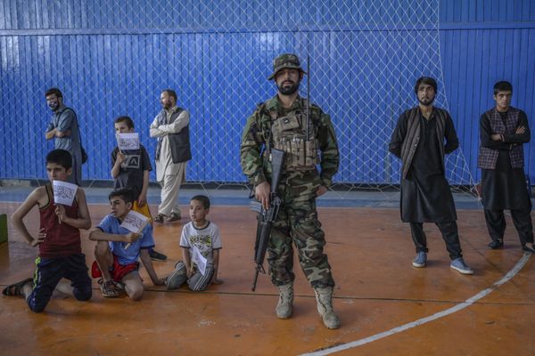 A Taliban fighter stands as youths wait to show their skills during an event organised for the visit of the Taliban's director of physical education and sports, Bashir Ahmad Rustamzai (not pictured), at a gymnasium in Kabul on 14 September 2021. - Sputnik International