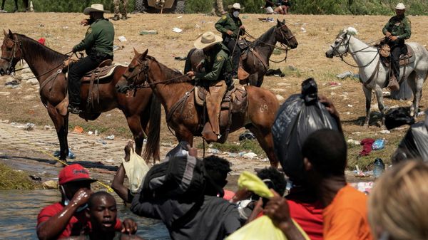 Migrants seeking asylum in the U.S. cross the Rio Grande river into the U.S. after obtaining food and supplies in Mexico as the U.S. Border Patrol agents monitor on a horse on the U.S. side of the bank near the International Bridge between Mexico and the U.S., in Del Rio Texas, U.S., where they wait to be processed, as seen from Ciudad Acuna, Mexico, September 20, 2021. - Sputnik International