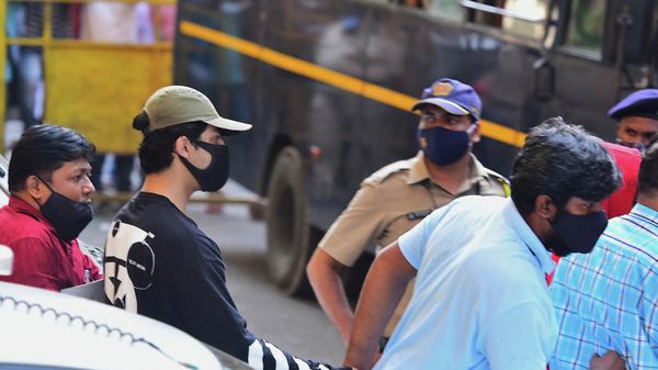 Bollywood actor Shah Rukh Khan's son Aryan Khan (2L) is being escorted by law enforcement officials outside the Narcotics Control Bureau (NCB) office after he was allegedly brought in for questioning along with others following a raid at a party on a cruise ship, in Mumbai on October 3, 2021 - Sputnik International