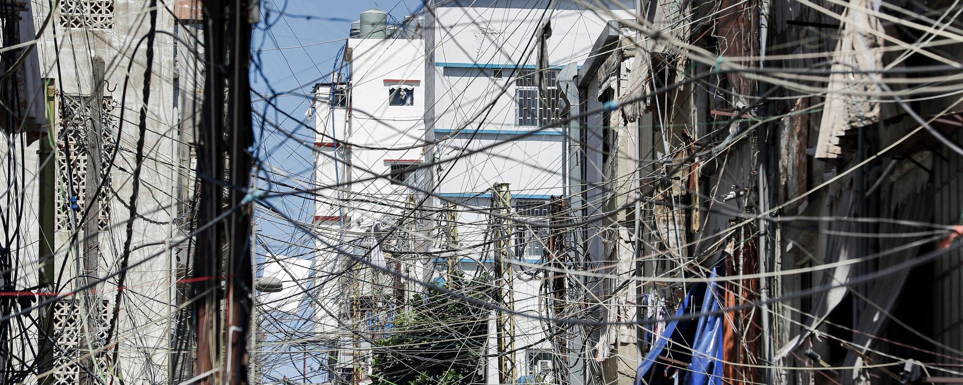 This file photo taken on June 23, 2021, shows a view of a mesh of raised electricity lines along a street in a suburb of Lebanon's capital Beirut. - Lebanon was plunged into a total blackout today after two main power stations went offline because they ran out of fuel, the state electricity corporation said. This file photo taken on June 23, 2021, shows a view of a mesh of raised electricity lines along a street in a suburb of Lebanon's capital Beirut. - Lebanon was plunged into a total blackout today after two main power stations went offline because they ran out of fuel, the state electricity corporation said. - Sputnik International, 1920, 14.10.2021