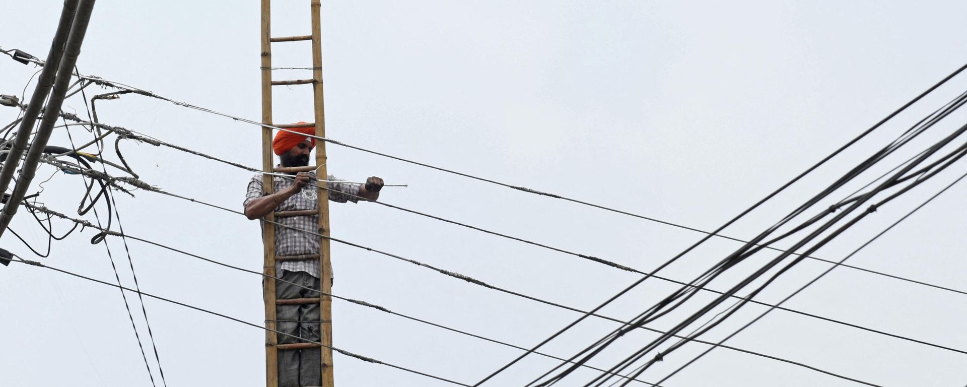 An employee of the Indian Punjab State Power Corporation Ltd, works on overhead electric cables in Amritsar on July 10, 2021 An employee of the Indian Punjab State Power Corporation Ltd, works on overhead electric cables in Amritsar on July 10, 2021 - Sputnik International, 1920, 11.10.2021