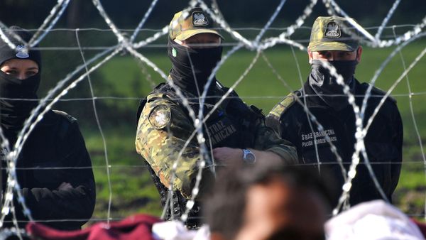 Polish border guards watch a refugee camp behind barbed wire installed on the border between Belarus and Poland near the village of Usnarz Dolny, Belarus - Sputnik International