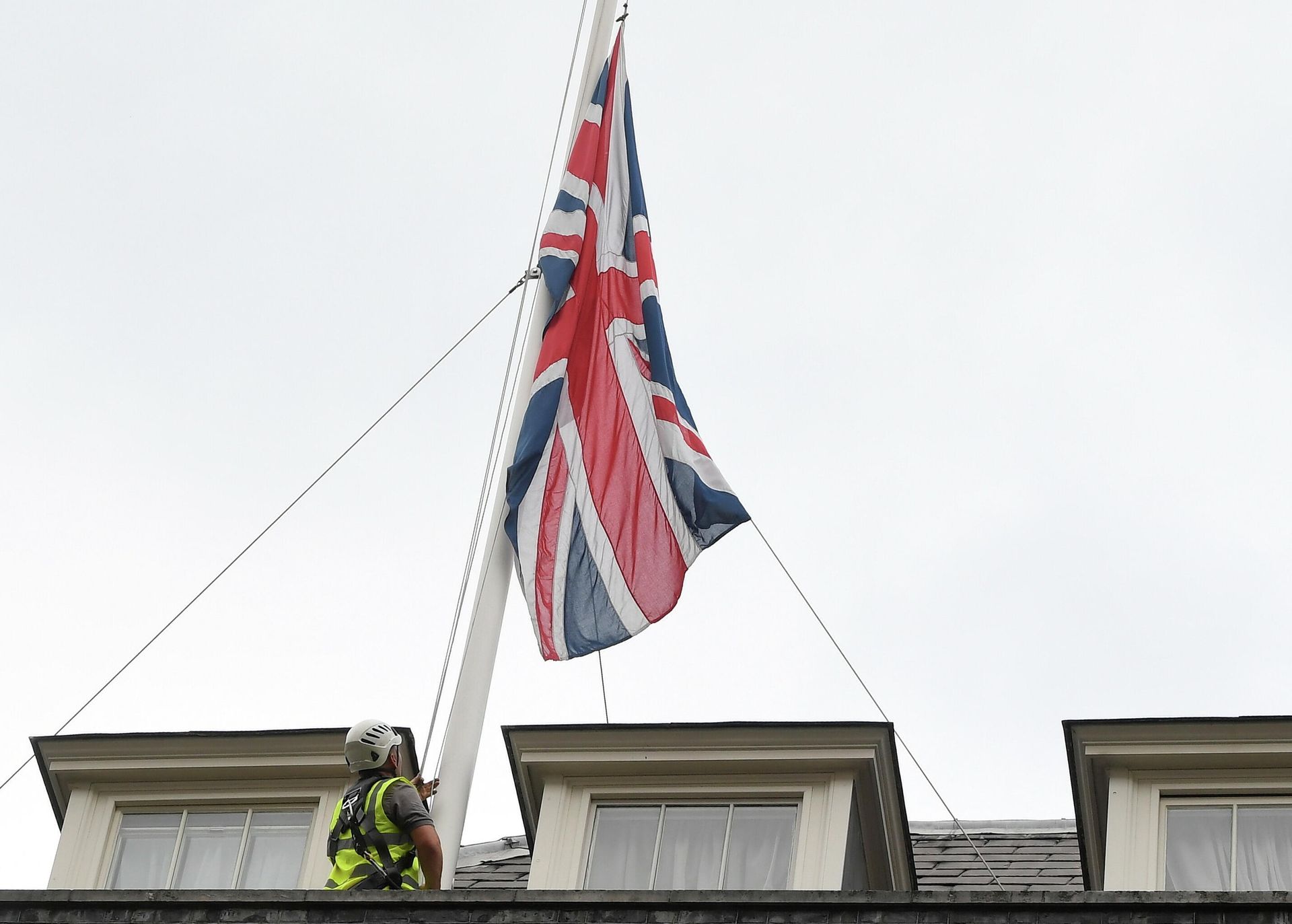 A worker lowers the Union flag over Downing Street after MP Sir David Amess was murdered - Sputnik International, 1920, 15.10.2021