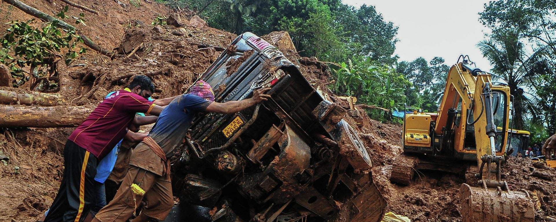 Rescue workers push a overturned vehicle stuck in the mud and debris at a site of a landslide claimed to be caused by heavy rains in Kokkayar in India's Kerala state on October 17, 2021 Rescue workers push a overturned vehicle stuck in the mud and debris at a site of a landslide claimed to be caused by heavy rains in Kokkayar in India's Kerala state on October 17, 2021 - Sputnik International, 1920, 18.10.2021