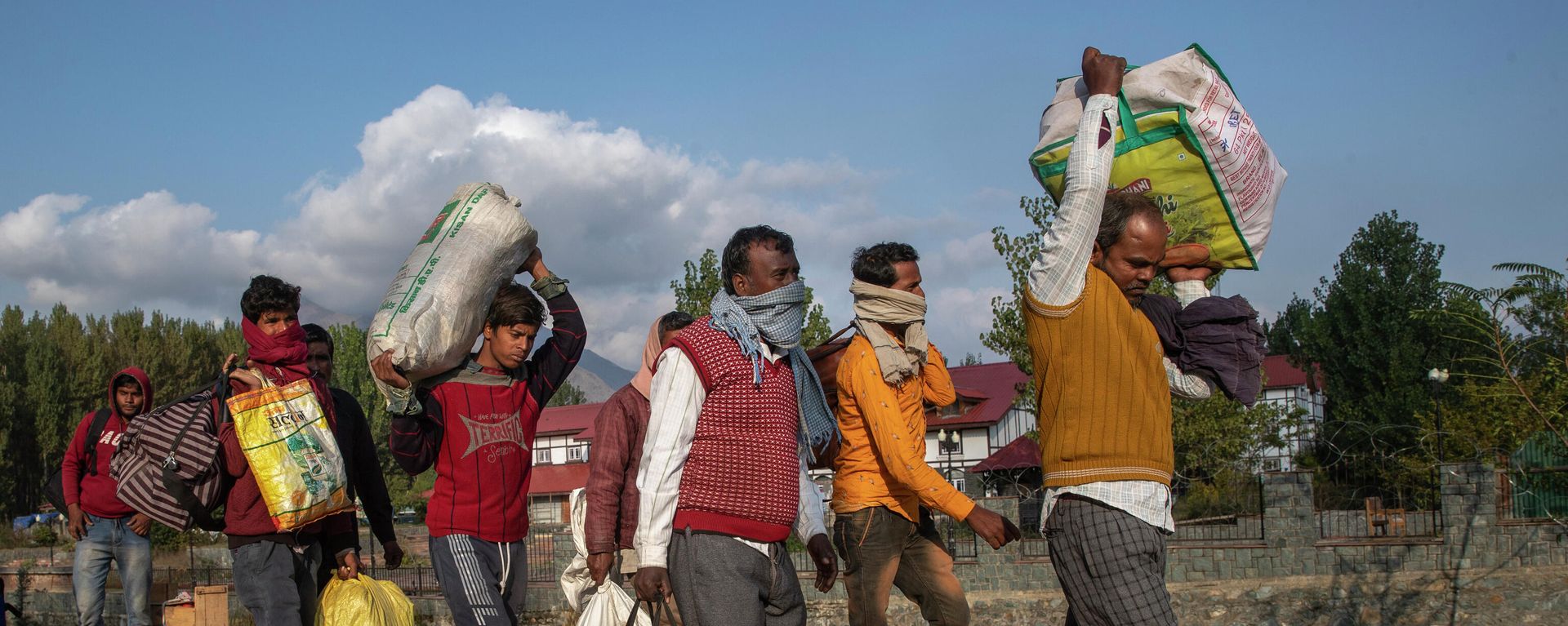 Indian migrant laborers leaving for their homes carry their belongings and walk towards a railway station on the outskirts of Srinagar, Indian controlled Kashmir, Monday, Oct. 18, 2021 - Sputnik International, 1920, 18.10.2021