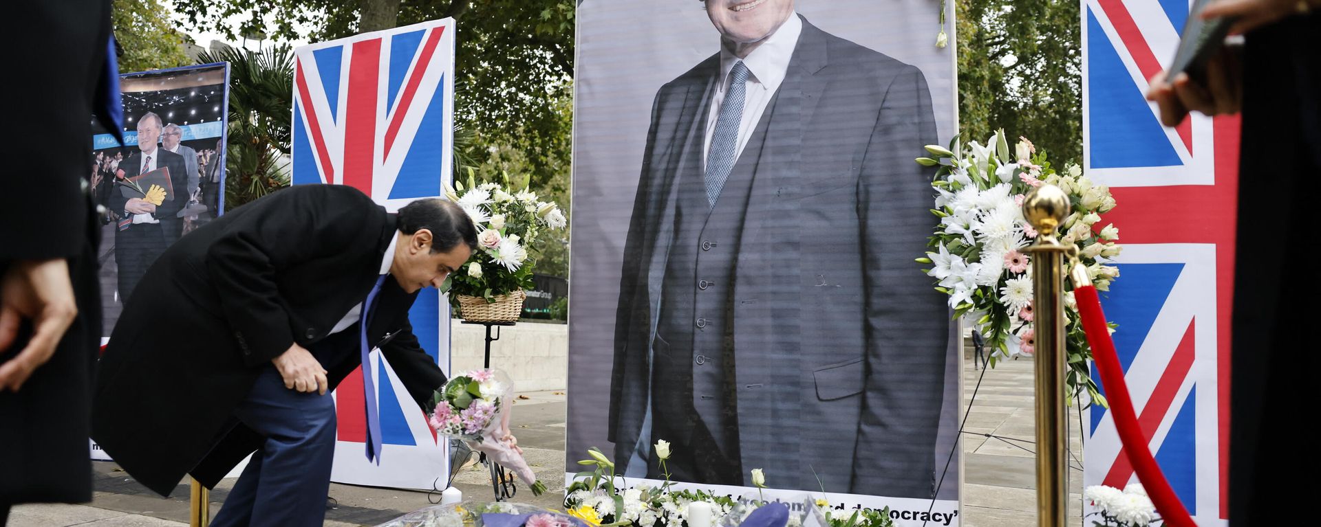 Members of the Anglo-Iranian community and supporters of the National Council of Resistance of Iran (NCRI) attend a memorial service to pay tribute to  slain British lawmaker David Amess in Parliament Square in front of the Houses of Parliament in central London on October 18, 2021 - Sputnik International, 1920, 19.10.2021