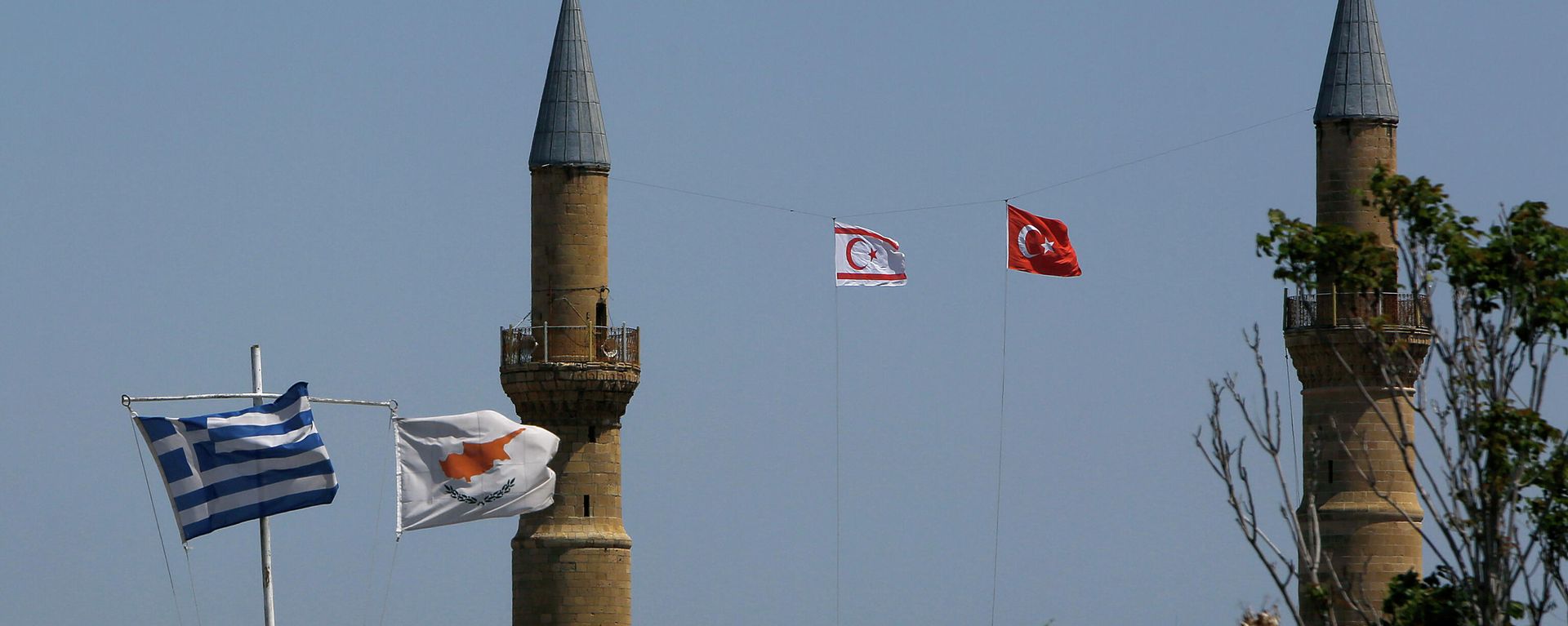 Greek, left, and Cyprus' flags, second left, flutter on poles in the south, as in the north Turkish occupied area, a Turkish and Turkish Cypriot breakaway flags fly on a minaret of the Selimiye mosque, or Cathedral of St Sophia, or Agia Sofia, in divided capital Nicosia, Cyprus, Monday, April 26, 2021 Greek, left, and Cyprus' flags, second left, flutter on poles in the south, as in the north Turkish occupied area, a Turkish and Turkish Cypriot breakaway flags fly on a minaret of the Selimiye mosque, or Cathedral of St Sophia, or Agia Sofia, in divided capital Nicosia, Cyprus, Monday, April 26, 2021 - Sputnik International, 1920, 26.09.2023