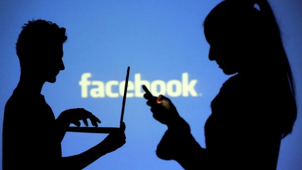 People are silhouetted as they pose with laptops in front of a screen projected with a Facebook logo, in this picture illustration taken in Zenica October 29, 2014 - Sputnik International