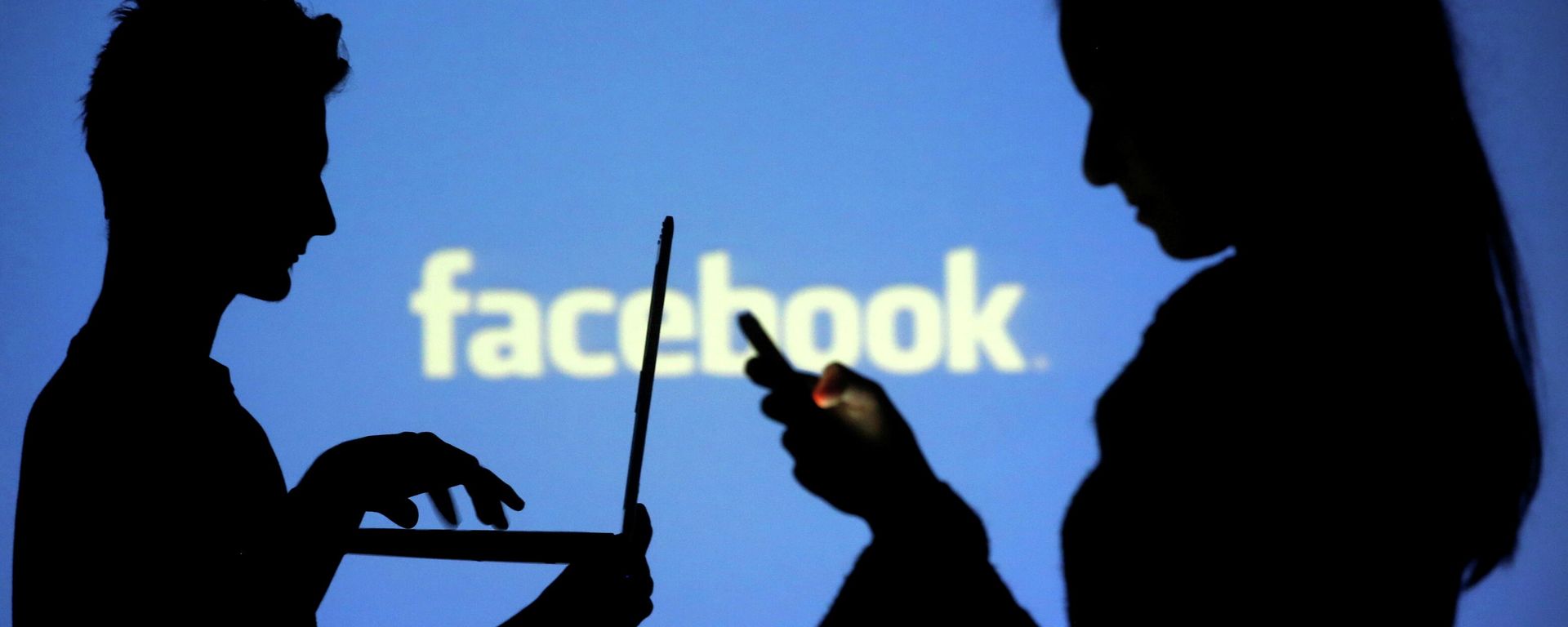 People are silhouetted as they pose with laptops in front of a screen projected with a Facebook logo, in this picture illustration taken in Zenica October 29, 2014 - Sputnik International, 1920, 24.10.2021