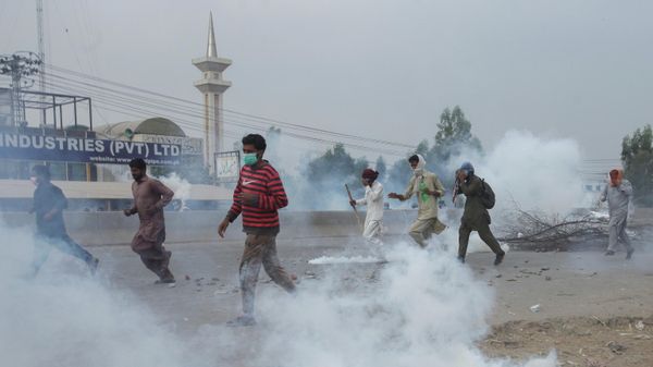 Supporters of the banned Islamist political party Tehrik-e-Labaik Pakistan (TLP) run amid the smoke of tear gas during a protest demanding the release of their leader and the expulsion of the French ambassador over cartoons depicting the Prophet Mohammed, in Lahore, Pakistan, October 23, 2021 - Sputnik International