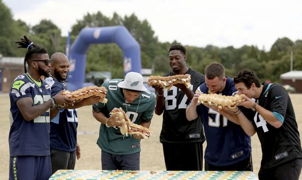 A wall of NFL players - from left, Seattle Seahawks' cornerback Neiko Thorpe, Tennessee Titans' defensive end Jurrell Casey, Philadelphia Eagles' wide receiver Mack Hollins, Oakland Raiders' tight end Jared Cook, Los Angeles Chargers' linebacker Kyle Emanuel and Jacksonville Jaguars' kicker Josh Lambo - pose with large sandwiches during an NFL flag schools event at King's House Sports Ground in Chiswick, west London on Wednesday 18 July 2018. - Sputnik International
