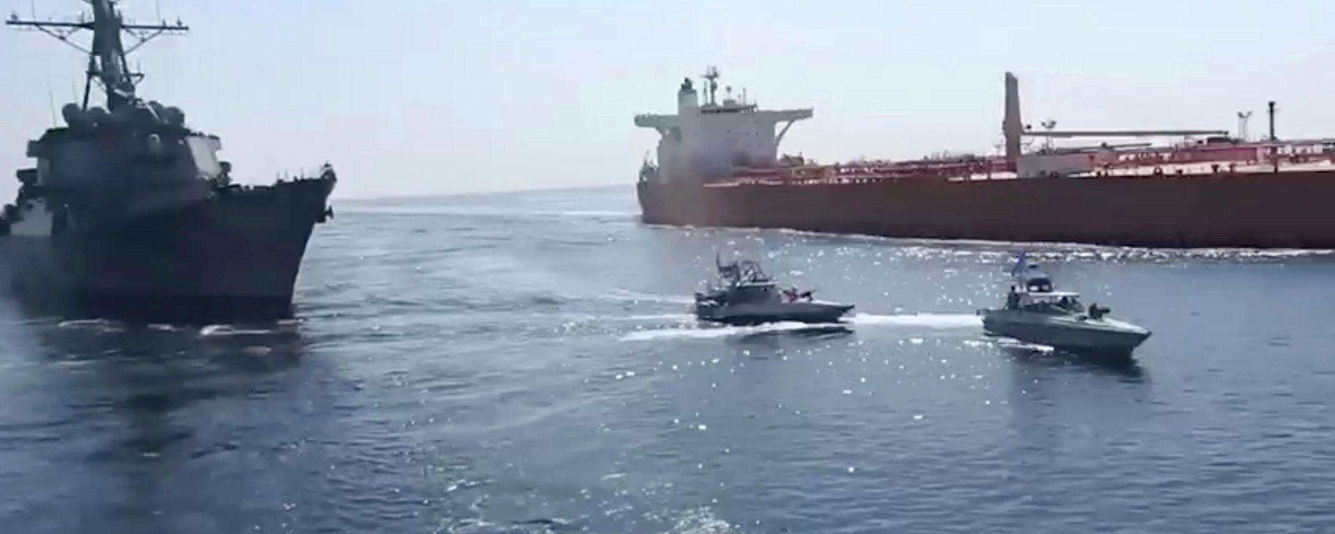 This frame grab from a video released by Iran's paramilitary Revolutionary Guard on Wednesday, Nov. 3, 2021, shows the Guard speed boats, center, in front of a U.S warship, left, amid the seizure of a Vietnamese-flagged oil tanker, right, in the Gulf of Oman. Iran seized the tanker in the Gulf of Oman last month and still holds the vessel, two U.S. officials told The Associated Press on Wednesday, revealing the latest provocation in Mideast waters as tensions escalate between Iran and the United States over Tehran's nuclear program. (Revolutionary Guard via AP) This frame grab from a video released by Iran's paramilitary Revolutionary Guard on Wednesday, Nov. 3, 2021, shows the Guard speed boats, center, in front of a U.S warship, left, amid the seizure of a Vietnamese-flagged oil tanker, right, in the Gulf of Oman. Iran seized the tanker in the Gulf of Oman last month and still holds the vessel, two U.S. officials told The Associated Press on Wednesday, revealing the latest provocation in Mideast waters as tensions escalate between Iran and the United States over Tehran's nuclear program. (Revolutionary Guard via AP) - Sputnik International, 1920, 04.11.2021