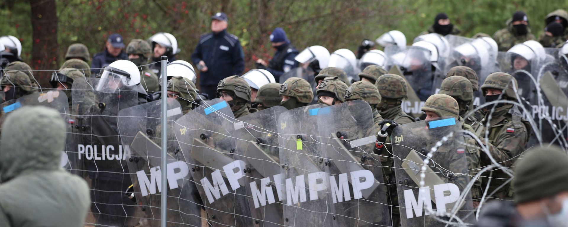 A picture taken on November 8, 2021 shows Poland's law enforcement officers watching migrants at the Belarusian-Polish border. A picture taken on November 8, 2021 shows Poland's law enforcement officers watching migrants at the Belarusian-Polish border. - Sputnik International, 1920, 12.11.2021
