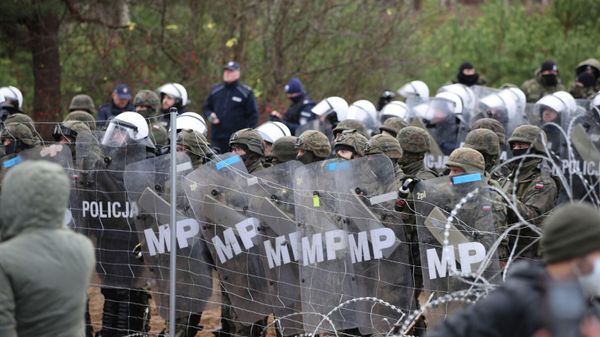 A picture taken on November 8, 2021 shows Poland's law enforcement officers watching migrants at the Belarusian-Polish border.  - Sputnik International