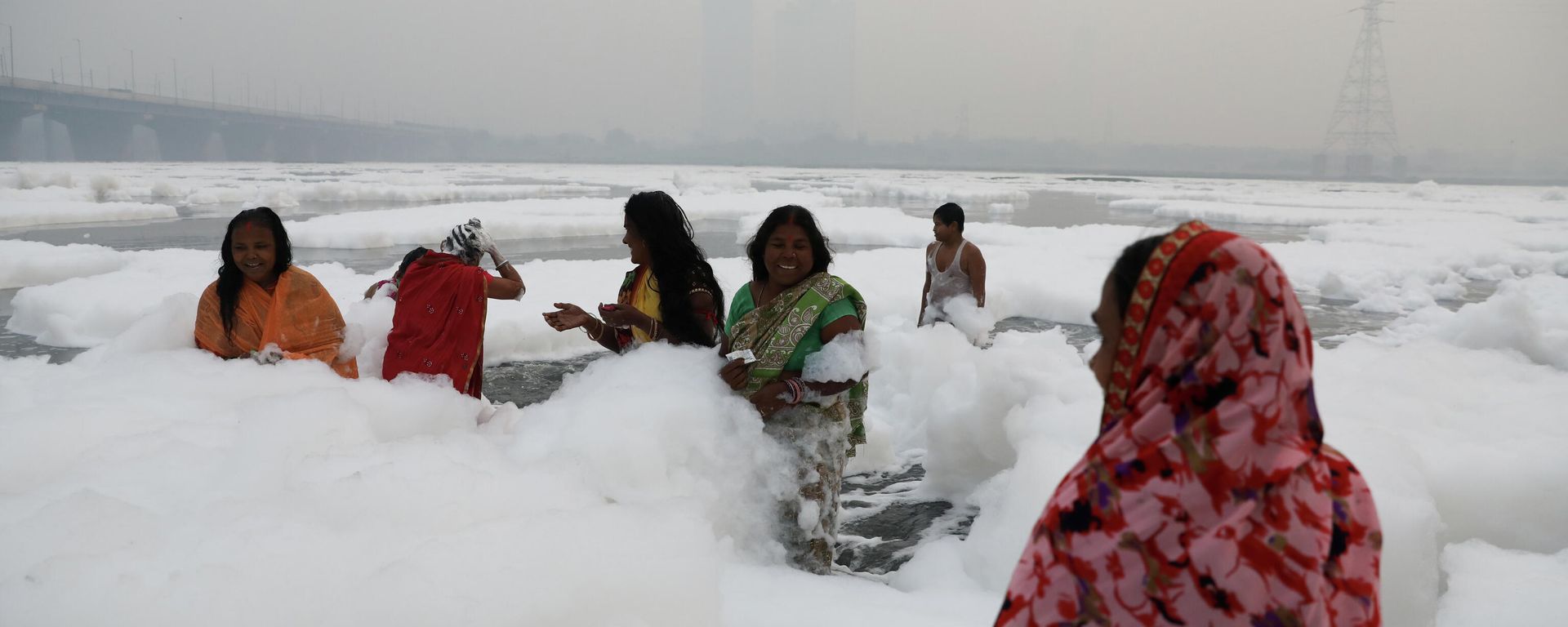 Women bathe themselves in the polluted waters of the river Yamuna on a smoggy morning in New Delhi - Sputnik International, 1920, 10.11.2021