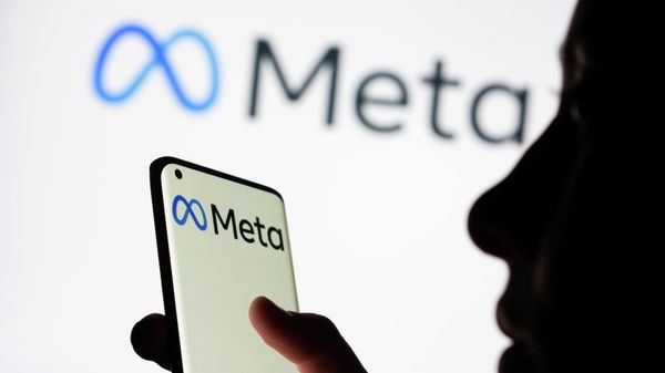 Woman holds smartphone with Meta logo in front of a displayed Facebook's new rebrand logo Meta - Sputnik International