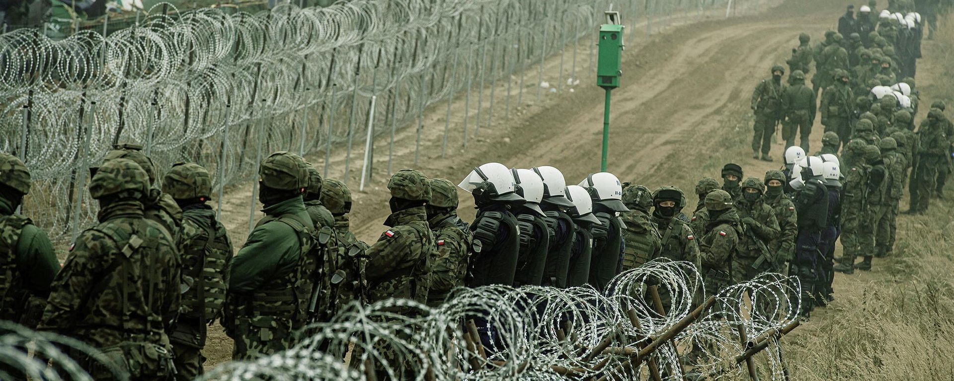 Polish soldiers and police watch migrants at the Poland/Belarus border near Kuznica, Poland, in this photograph released by the Territorial Defence Forces, November 12, 2021 Polish soldiers and police watch migrants at the Poland/Belarus border near Kuznica, Poland, in this photograph released by the Territorial Defence Forces, November 12, 2021 - Sputnik International, 1920, 28.11.2021