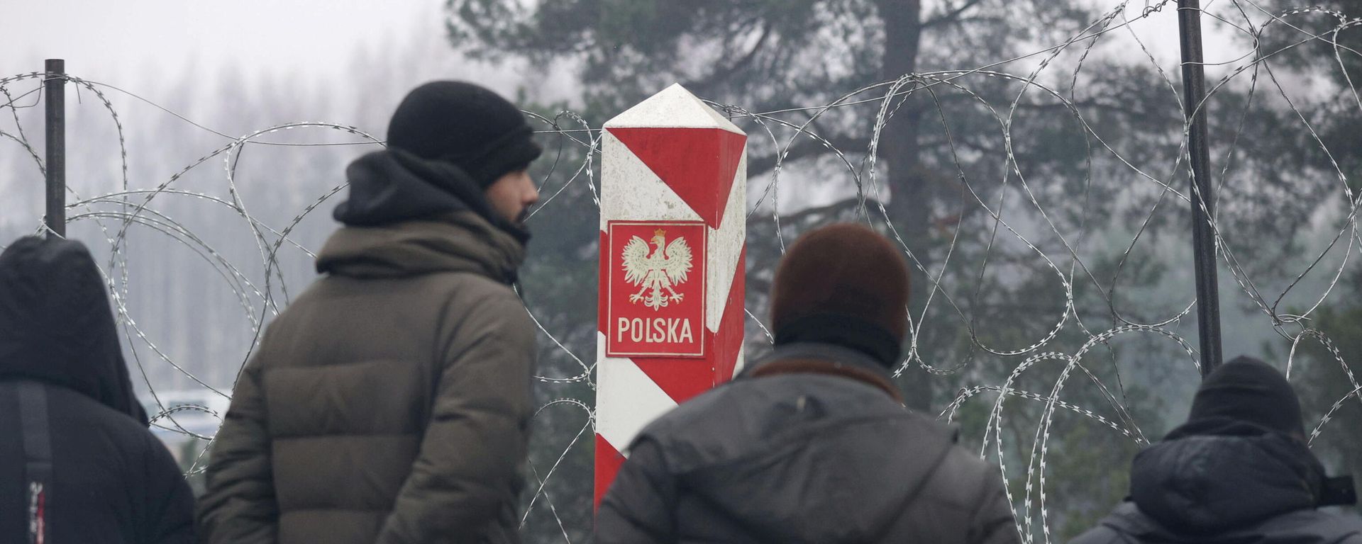 People gather near a barbed wire fence in a migrants' makeshift camp on the Belarusian-Polish border in the Grodno region, Belarus November 14, 2021 People gather near a barbed wire fence in a migrants' makeshift camp on the Belarusian-Polish border in the Grodno region, Belarus November 14, 2021 - Sputnik International, 1920, 15.11.2021