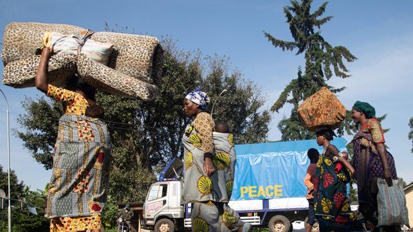 A group of Democratic Republic of Congo (DRC) asylum-seekers carrying their belongings walk past a truck reading PEACE at the Bunagana border point in Uganda, on November 10, 2021  following a deadly fight between M23 rebels and DRC troops. - Sputnik International