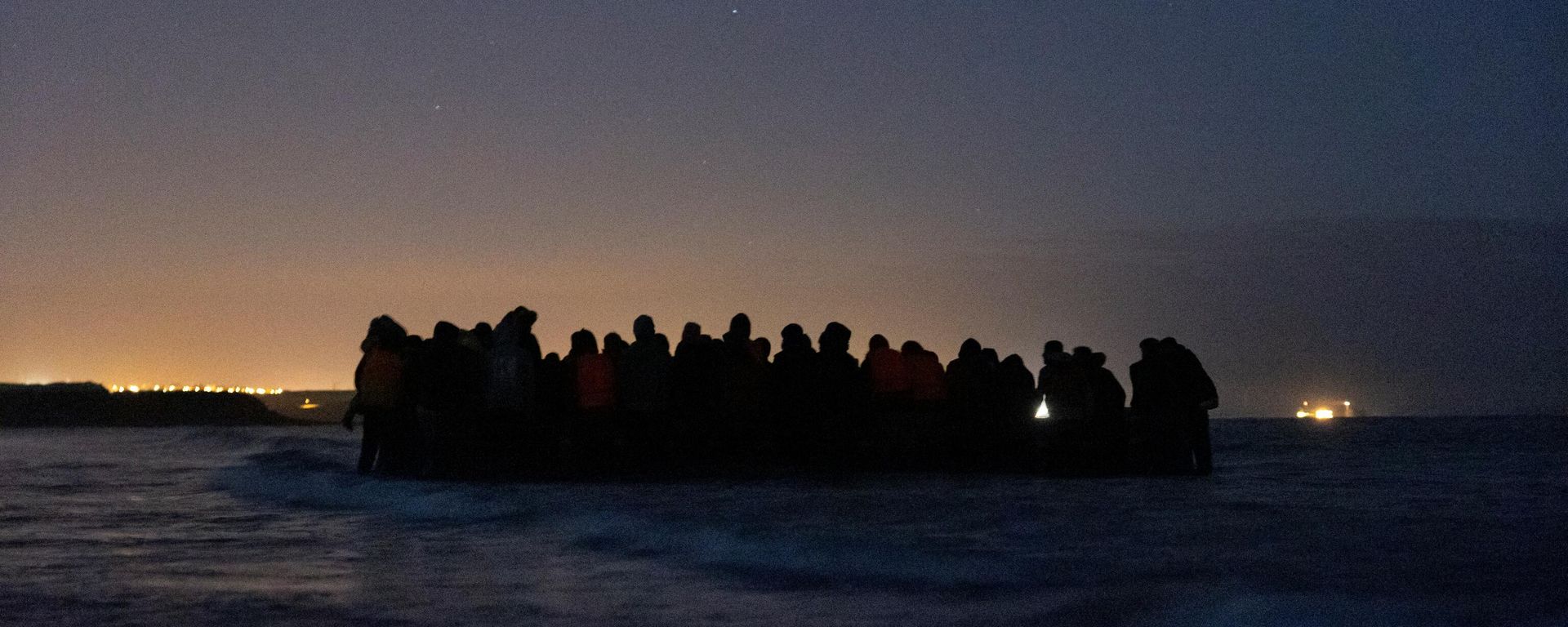 A group of 80 migrants get on one of the inflatable boats to cross the Channel towards England at night, near Wimereux, northern France, on October 16, 2021 - Sputnik International, 1920, 19.11.2021