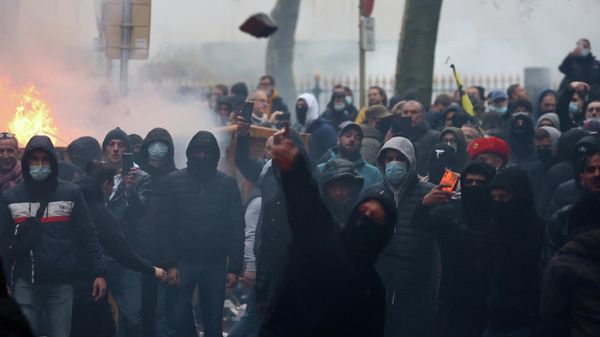 A protester throws stones towards riot police as clashes erupt during a demonstration against Covid-19 measures, including the country's health pass, in Brussels on November 21, 2021.  - Sputnik International