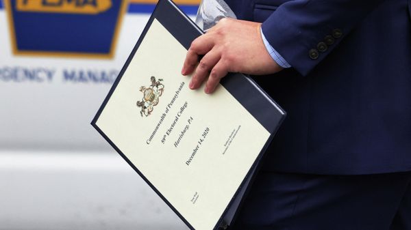 A Pennsylvania State elector holds an electoral college binder after exiting the Forum Auditorium after casting his vote in the 2020 Presidential election on December 14, 2020 in Harrisburg, Pennsylvania. Electors in Pennsylvania will meet today to certify the 2020 presidential election for President-elect Joe Biden who won the electoral college 306-to-232 against incumbent President Donald Trump. On Friday, the Supreme Court tossed out a lawsuit filed by Texas that intended to overturn Biden's win in four battleground states that included Pennsylvania. - Sputnik International