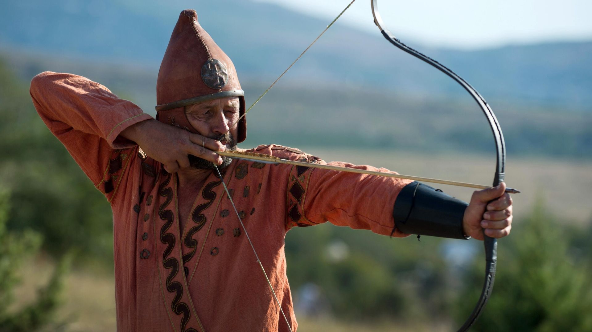 Participant of the Scolotoi Nomad Camp reenactment shoots a bow at the Crimean military historical festival in Pervomaika, Balaklava District Participant of the Scolotoi Nomad Camp reenactment shoots a bow at the Crimean military historical festival in Pervomaika, Balaklava District - Sputnik International, 1920, 29.11.2021