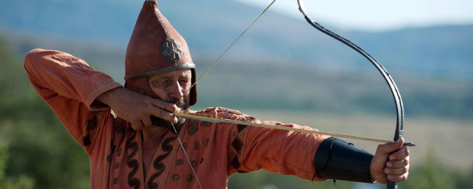 Participant of the Scolotoi Nomad Camp reenactment shoots a bow at the Crimean military historical festival in Pervomaika, Balaklava District - Sputnik International, 1920, 29.11.2021
