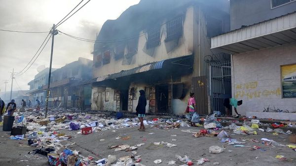 People stand amid debris in front of a burned-out building after days of unrest in Honiara, Solomon Islands November 26, 2021. - Sputnik International
