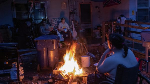 Members of the Bowlin family keep warm next to a wood fire in the front yard of their home after losing power in the aftermath of a tornado in Mayfield, Kentucky, U.S. December 14, 2021 - Sputnik International