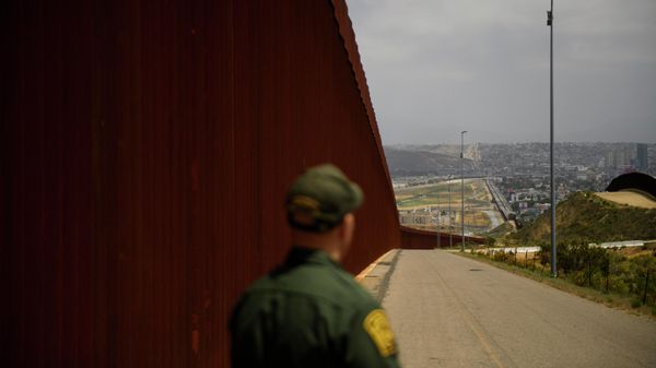 A US Border Patrol agent looks back towards the San Ysidro port of entry while standing next to a new section of the steel bollard-style border wall along the US-Mexico border between San Diego sand Tijuana, during a tour with the US Customs and Border Protection on May 10, 2021 in San Diego County, California. - Few issues have as long a history of bedeviling both Democrats and Republicans as immigration and asylum on the approximately 2,000-mile (3,000-kilometer) US-Mexico frontier. - Sputnik International