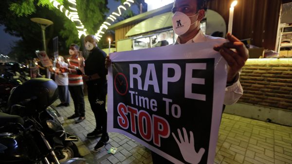 A man holds a poster  and candle during a protest against the alleged gang rape and killing of a Dalit woman, in Ahmedabad, India, Tuesday, Oct. 6, 2020.  - Sputnik International