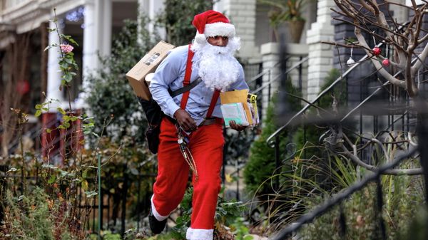 Postal worker Eddie Smith, dressed as Santa Claus, waves to a neighbor on his mail route in Washington, U.S., December 21, 2021 - Sputnik International