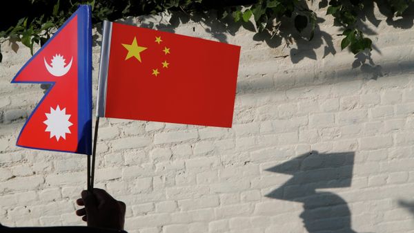 A Nepalese man holds Chinese and Nepalese flags as he waits to welcome Chinese president Xi Jinping in Kathmandu, Nepal, Saturday, Oct 12, 2019.  - Sputnik International