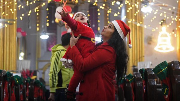 A child dressed as Santa Claus is held up by her mother on the eve of Christmas at St Paul's church in Amritsar, India, on 24 December 2021.  - Sputnik International