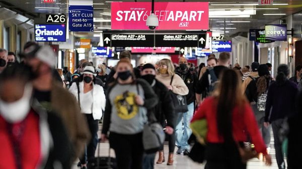 Travelers are seen under a PSA advising social distancing in a concourse during the holiday season as the coronavirus Omicron variant threatens to increase case numbers at Hartsfield-Jackson Atlanta International Airport in Atlanta, Georgia, U.S. December 22, 2021. - Sputnik International