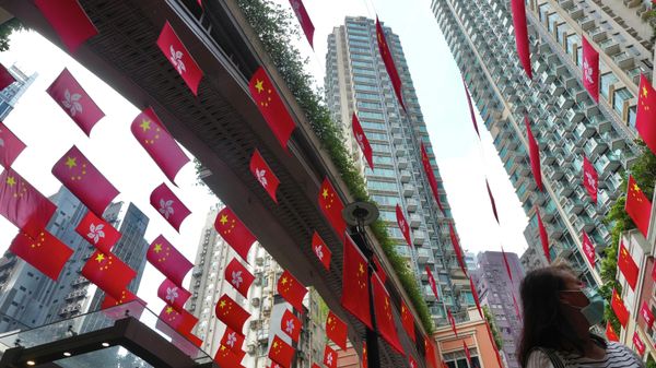 A woman walks past  Chinese national and Hong Kong flags marking China's 72nd National Day in Hong Kong Friday, Oct. 1, 2021. - Sputnik International