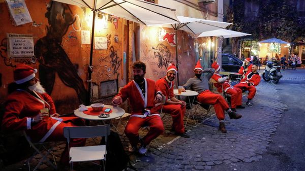 Men dressed in Santa suits sit in outdoor tables in Trastevere one day before Italy goes back to a complete lockdown as part of efforts put in place to curb the spread of the coronavirus disease (COVID-19), in Rome, Italy, December 23, 2020. - Sputnik International
