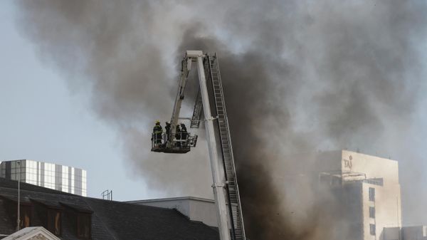 Firefighters are seen on a ladder of a fire engine as smoke billows from the roof of a building at the South African Parliament precinct in Cape Town - Sputnik International