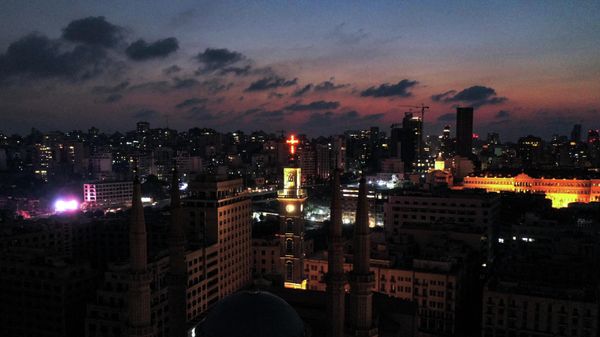 This picture taken on October 11, 2021 shows an aerial view of the lit bell-tower of the Saint George Maronite Cathedral and the unlit minarets of the Mohammed al-Amin mosque near the Martyrs' Square in the centre of Lebanon's capital Beirut, with buildings in darkness during a power outage. (Photo by AFP) - Sputnik International