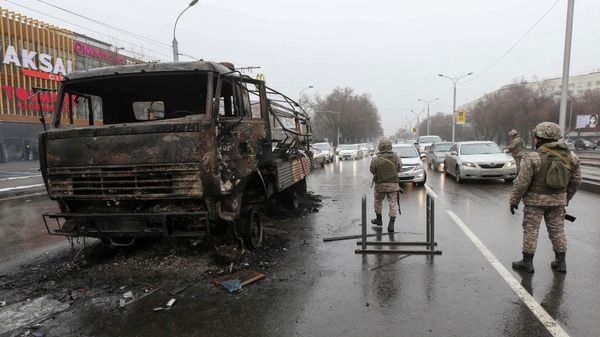 Kazakh law enforcement officers stand guard near a burnt truck while checking vehicles in a street, after mass protests triggered by fuel price increase erupted all over the country, in Almaty, Kazakhstan January 8, 2022. - Sputnik International